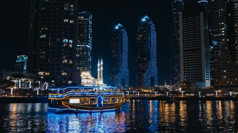 Cruise boat sailing through Dubai Marina skyline at night
